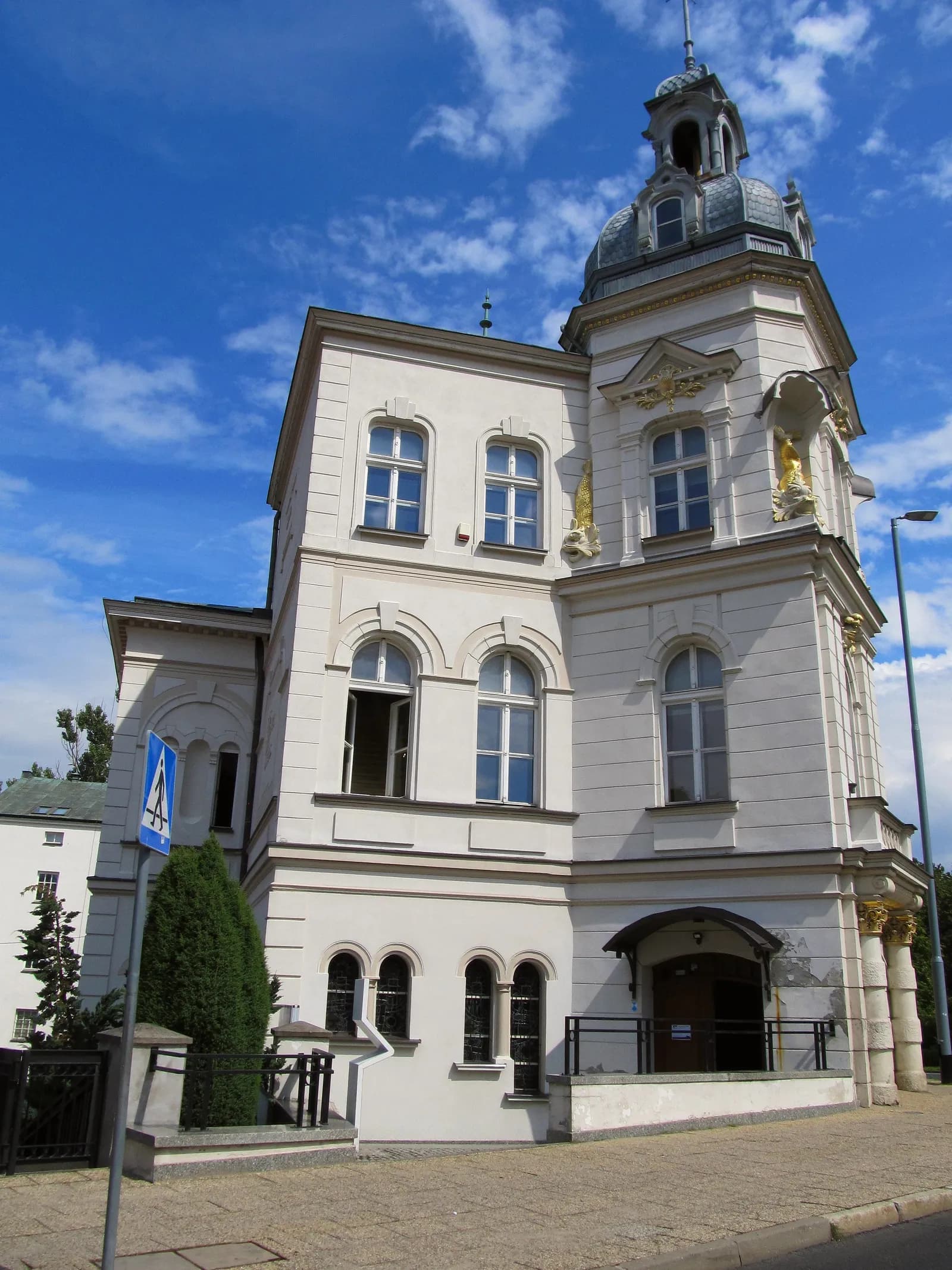 A historic white building with a gray domed tower against a blue sky with white clouds.